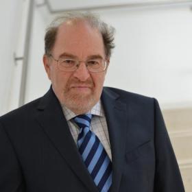 A man in a suit and tie standing in front of stairs.