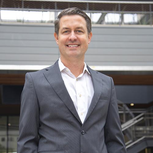 Man in blazer in front of building.