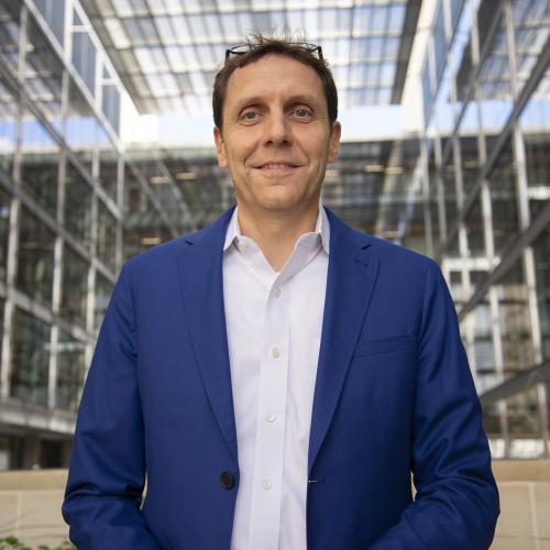 Man smiling in front of building.