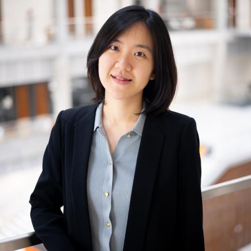 Woman in blazer leaning on a rail.